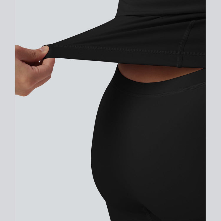 Person wearing a black long-sleeve top and leggings against a light gray background