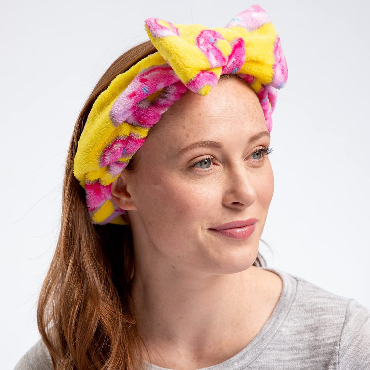 A woman wearing a multicolored geometric patterned headband with a large bow.