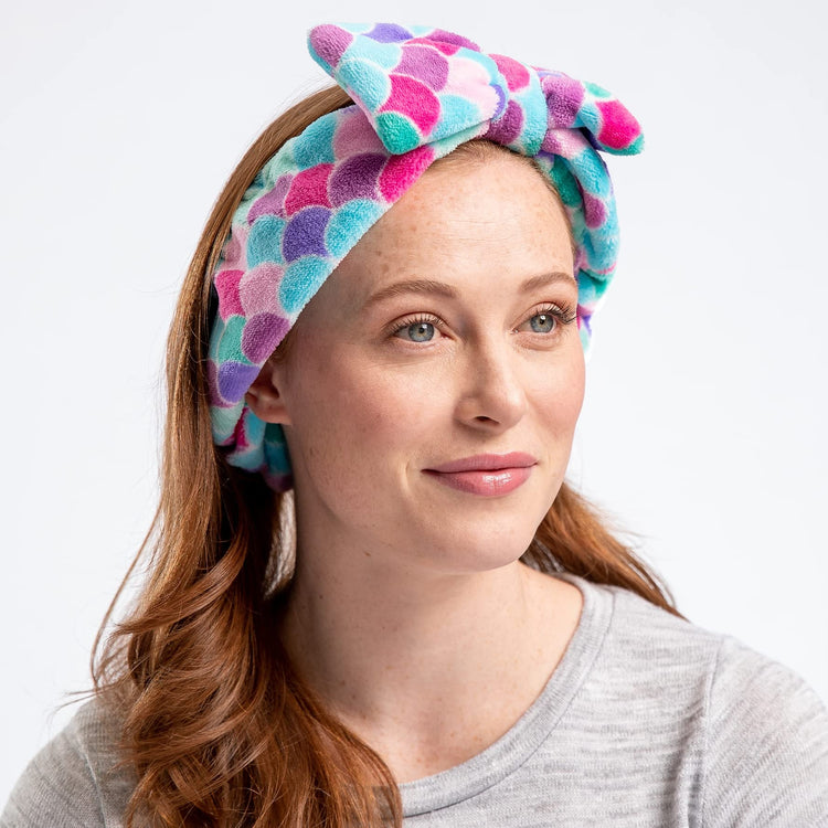 A woman wearing a multicolored geometric patterned headband with a large bow.