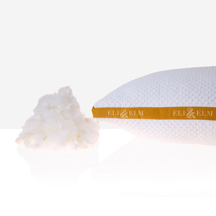 A woman sitting on a yellow couch, hugging a white and orange striped pillow with a smile on her face.