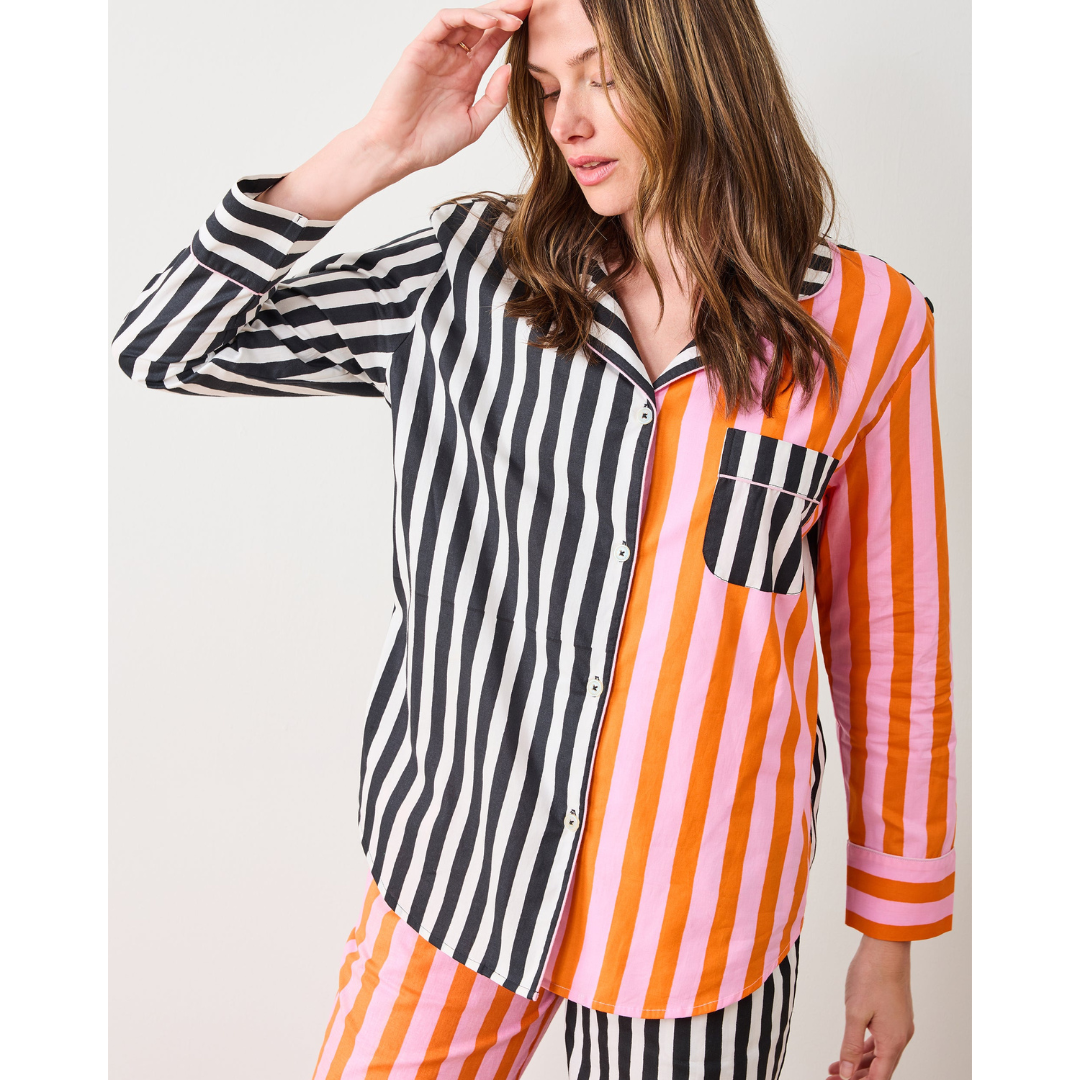 Person wearing a striped shirt with black, orange, and pink vertical stripes on a plain background