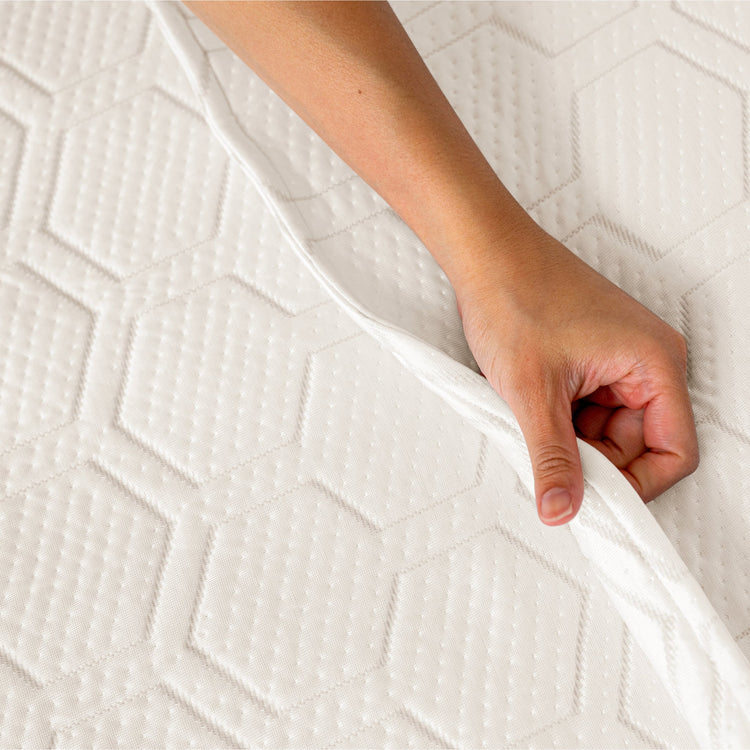 Hand touching a textured white mattress