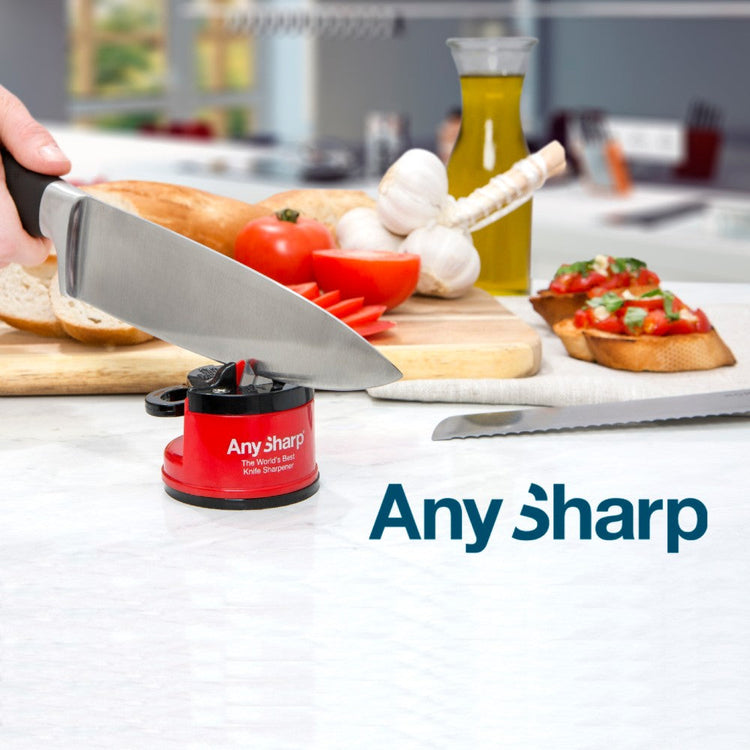 A knife being sharpened using the AnySharp Knife Sharpener Pro, placed on a kitchen counter with food ingredients in the background.