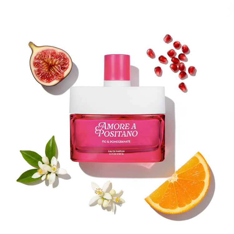 Pink and white perfume bottle labeled 'Amore a Positano' with fig, pomegranate, orange, and flower elements on a white background.