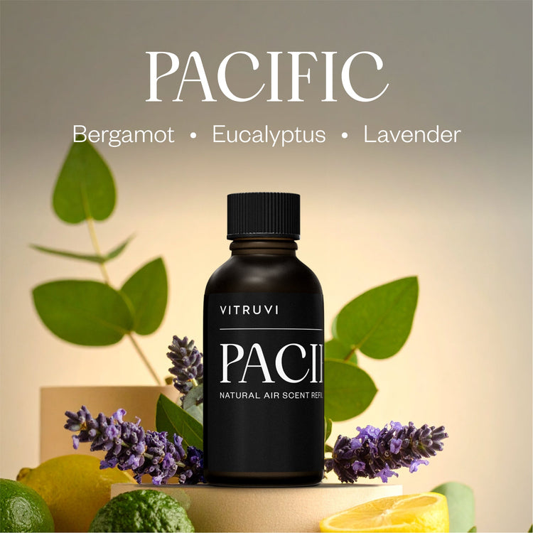 Black bottle of Vitruvi Pacific air scent refill with green leaves and lavender flowers on a neutral background
