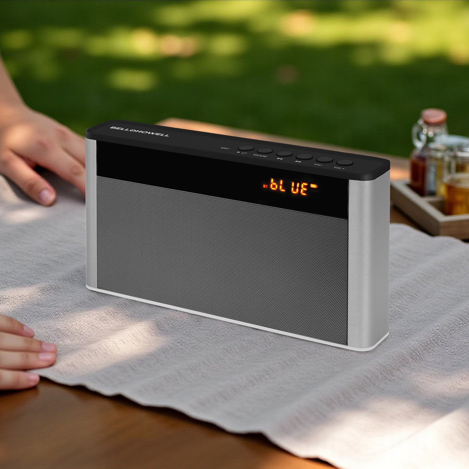 Bluetooth speaker on a table with a blurred outdoor background