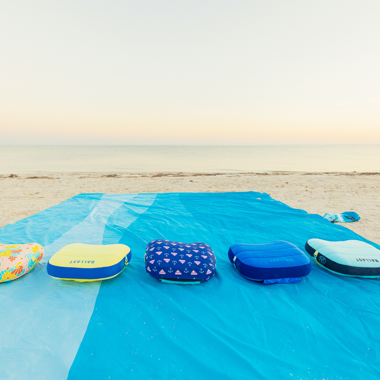 Inflatable beach toys on a blue towel with a beach and ocean background