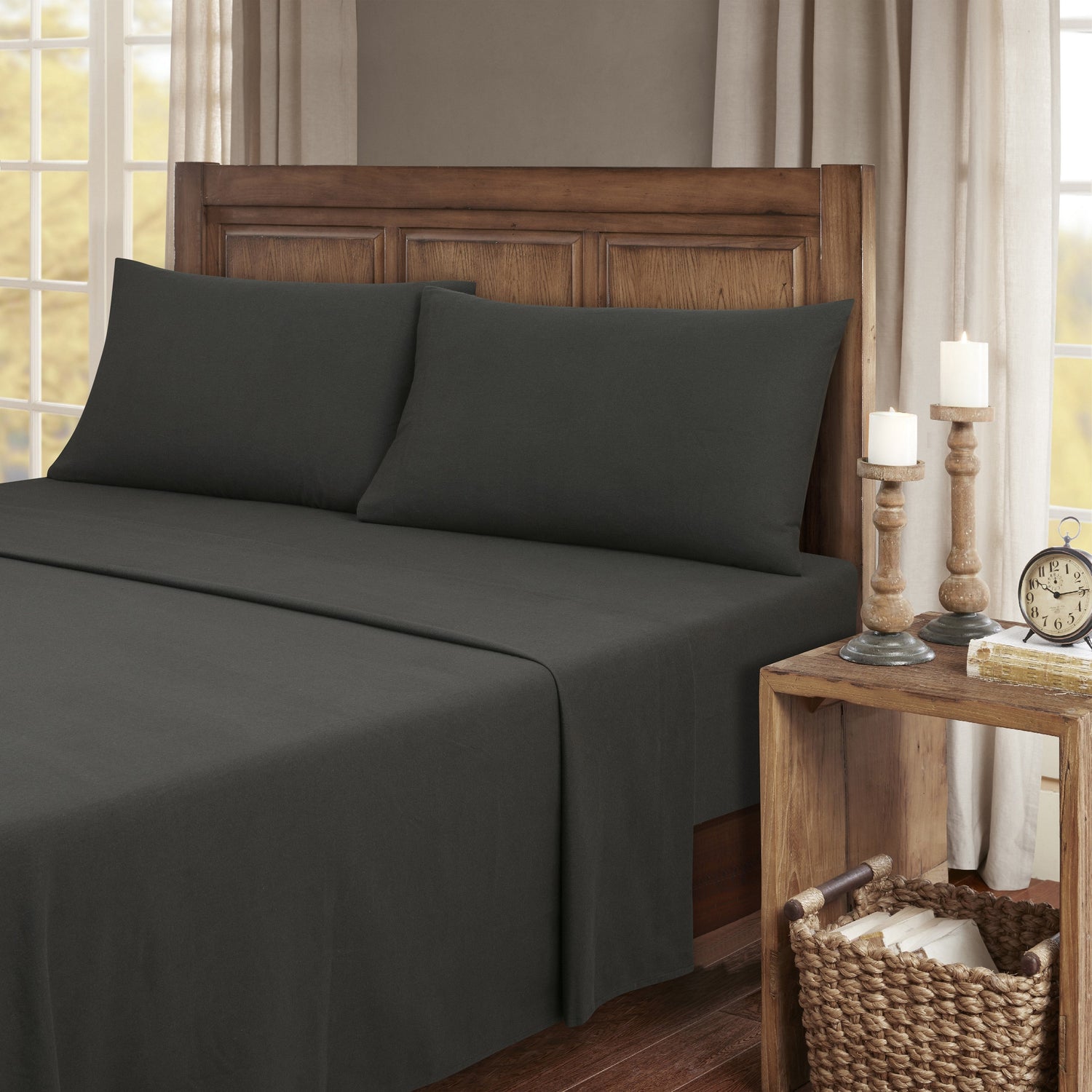 Dark gray bedding set on a bed with wooden headboard and nightstand in a bedroom setting.