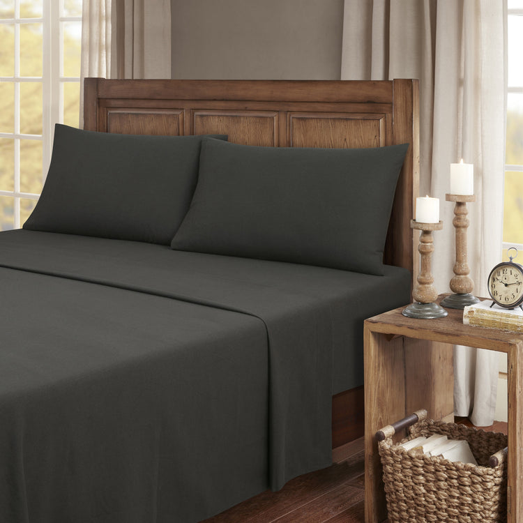 Dark gray bedding set on a bed with wooden headboard and nightstand in a bedroom setting.