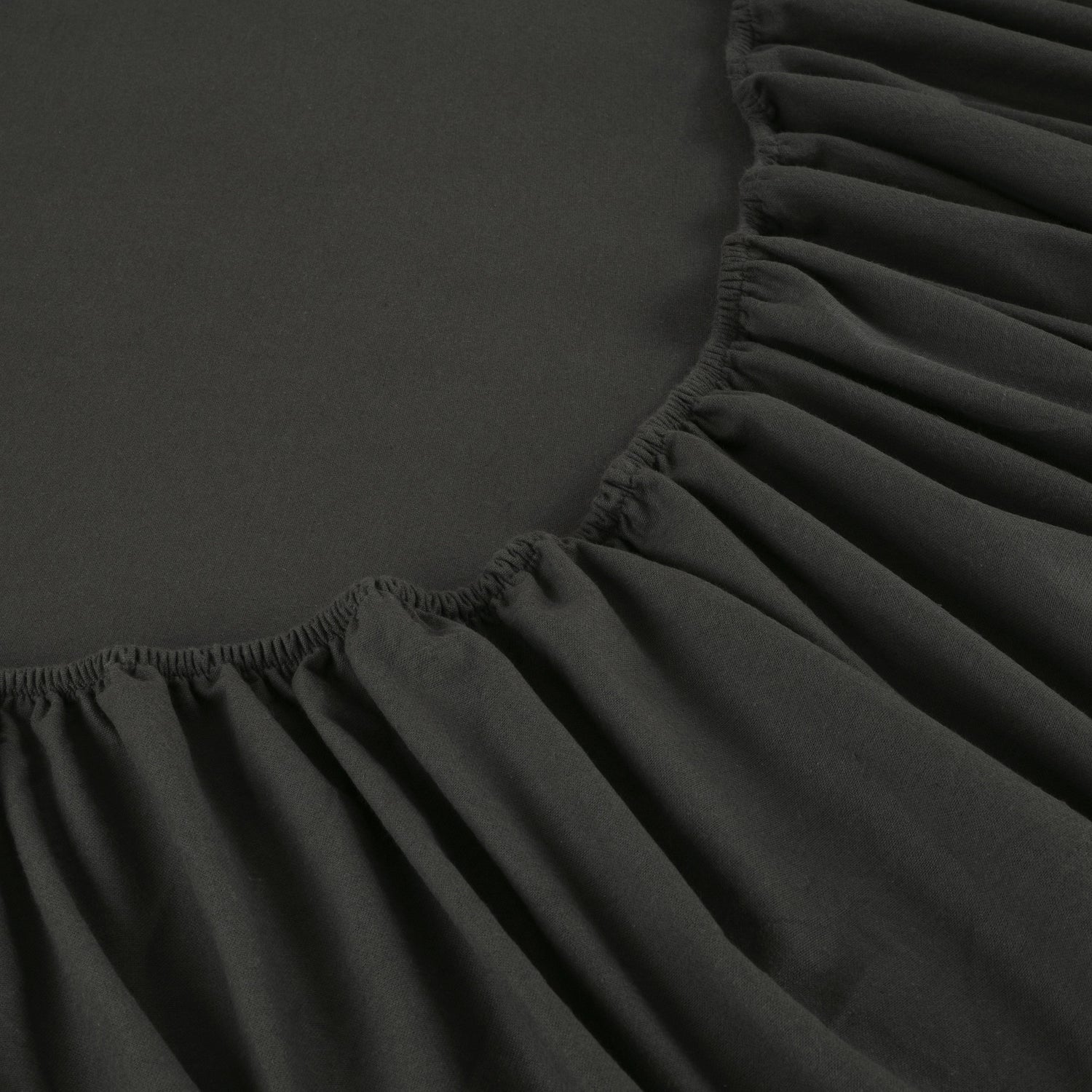 Black fitted sheet on a bed with a close-up view of the fabric texture.