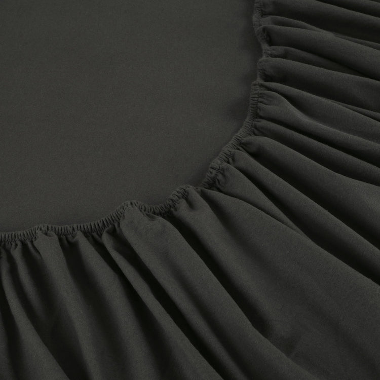Black fitted sheet on a bed with a close-up view of the fabric texture.