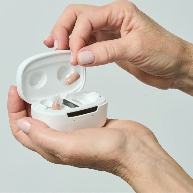 Person holding a white case with earbuds against a light gray background