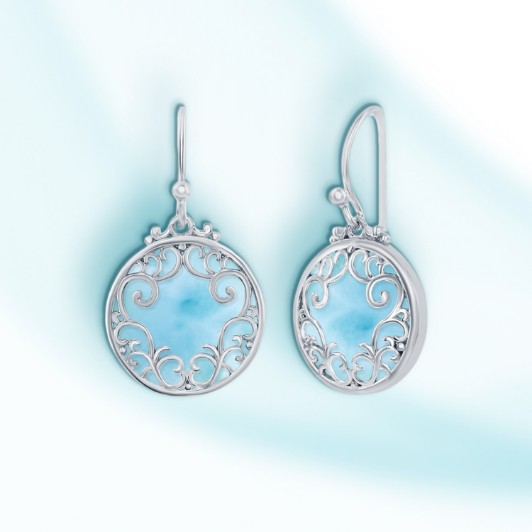 Silver earrings with intricate designs on a light blue gradient background