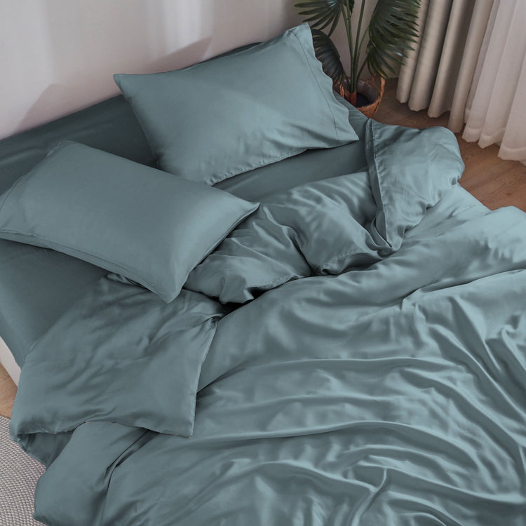 Teal bedding set on a bed with pillows in a bedroom setting.