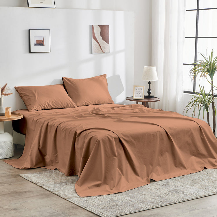 Brown bedspread set on a bed in a well-lit room with decor elements.