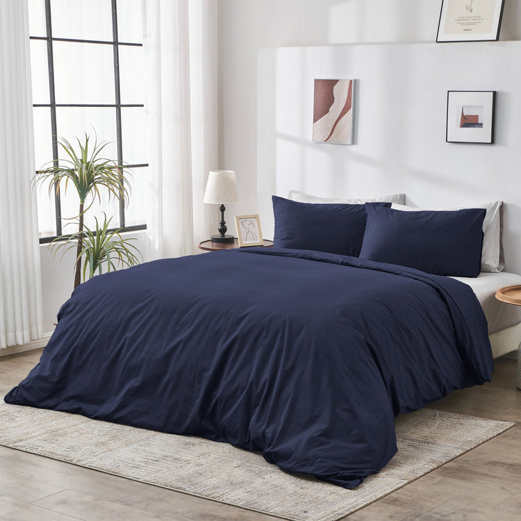 Navy blue bedding set on a bed in a well-lit bedroom with decor elements.