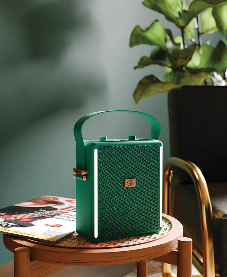 Green portable speaker on a wooden table with a plant in the background