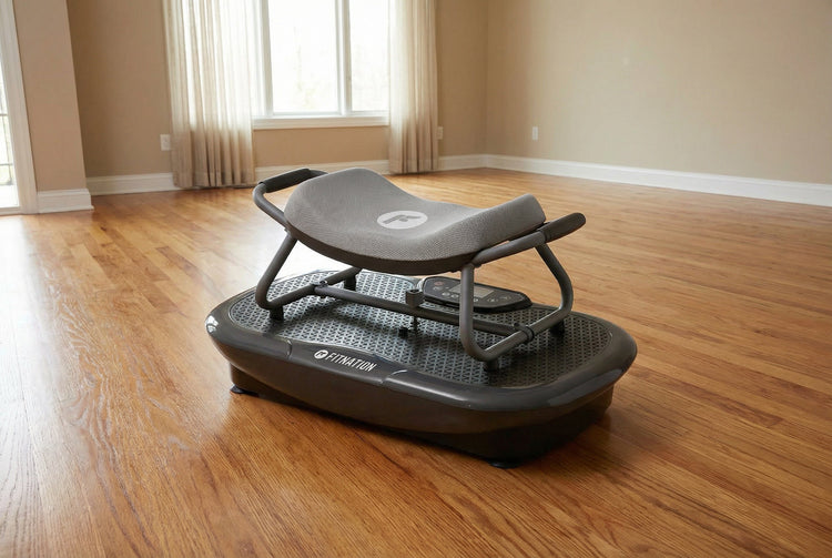 Black vibration plate on a wooden floor in a room with beige walls and curtains.