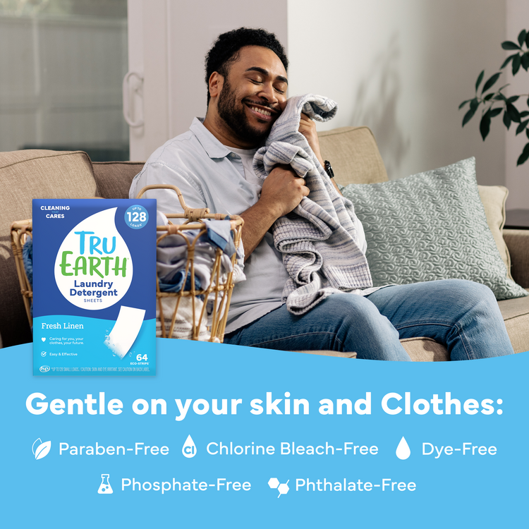 Man sitting on a couch holding a blanket with Tru Earth laundry detergent packaging displayed.