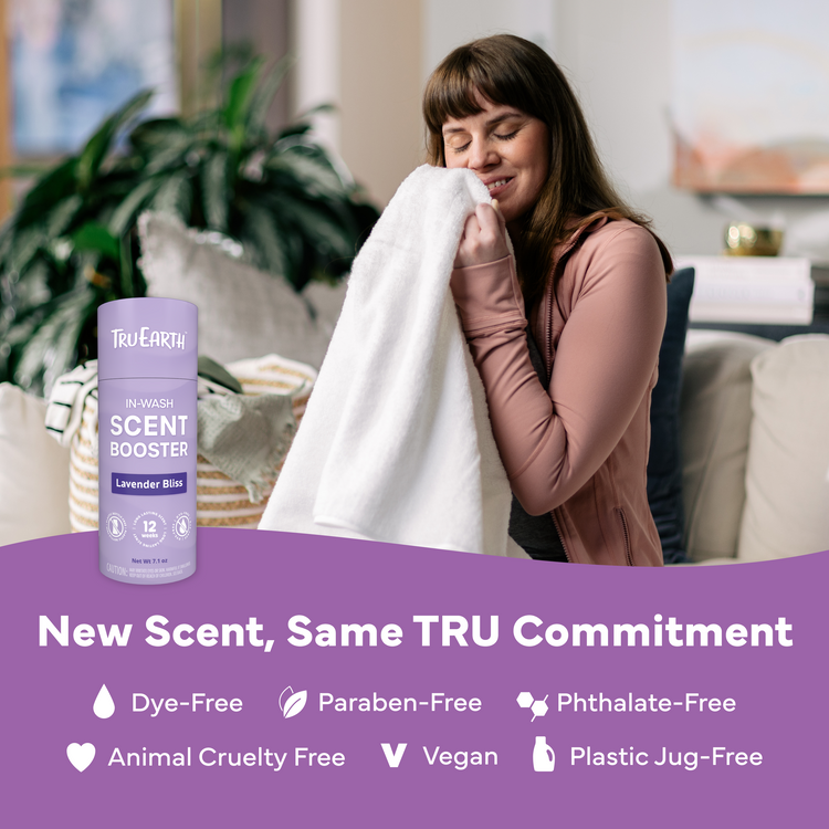 Woman holding a towel next to a bottle of Tru Earth In Wash Scent Booster in a living room setting.