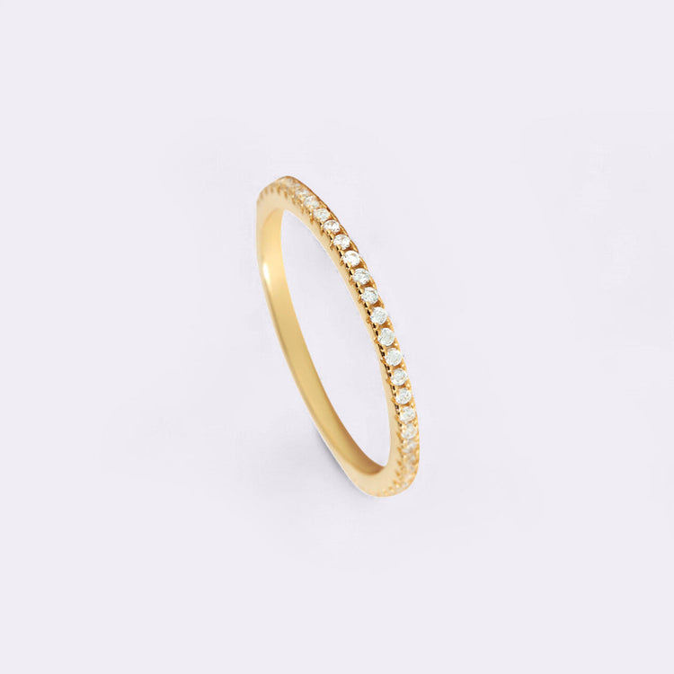 Gold ring with small diamonds on a light gray background