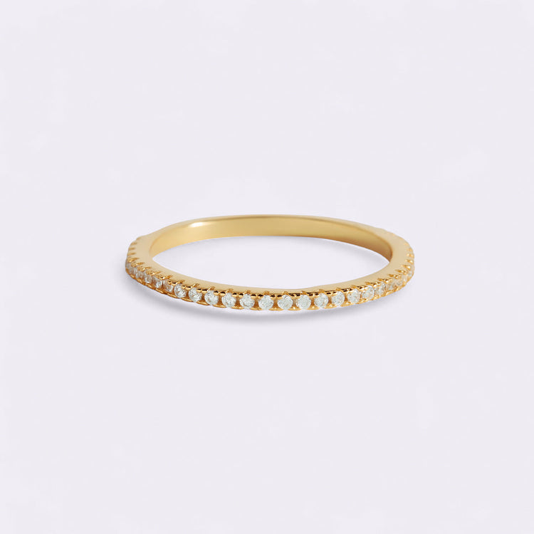Gold ring with small diamonds on a light gray background