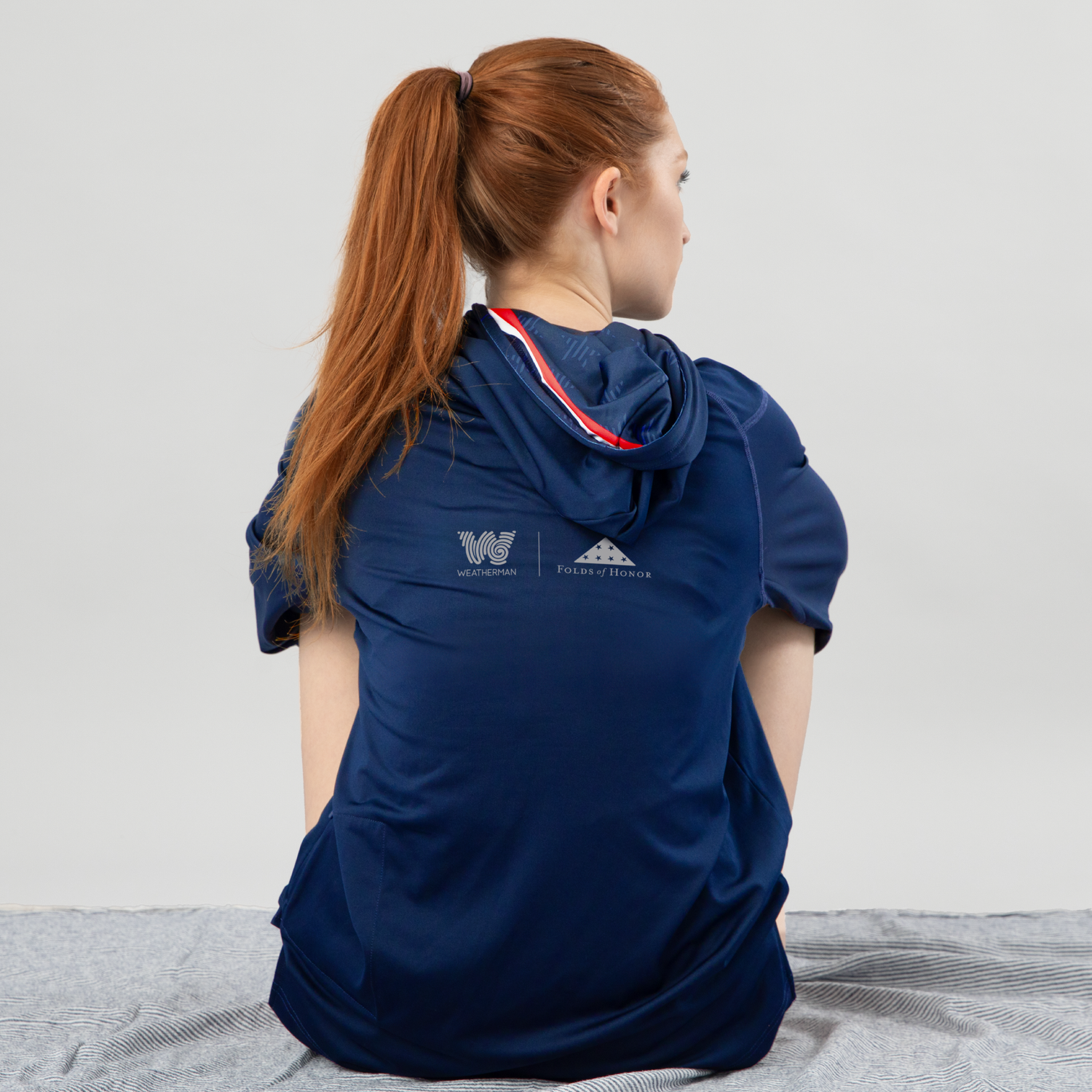 Woman sitting and wearing Folds of Honor Sun Shirt.