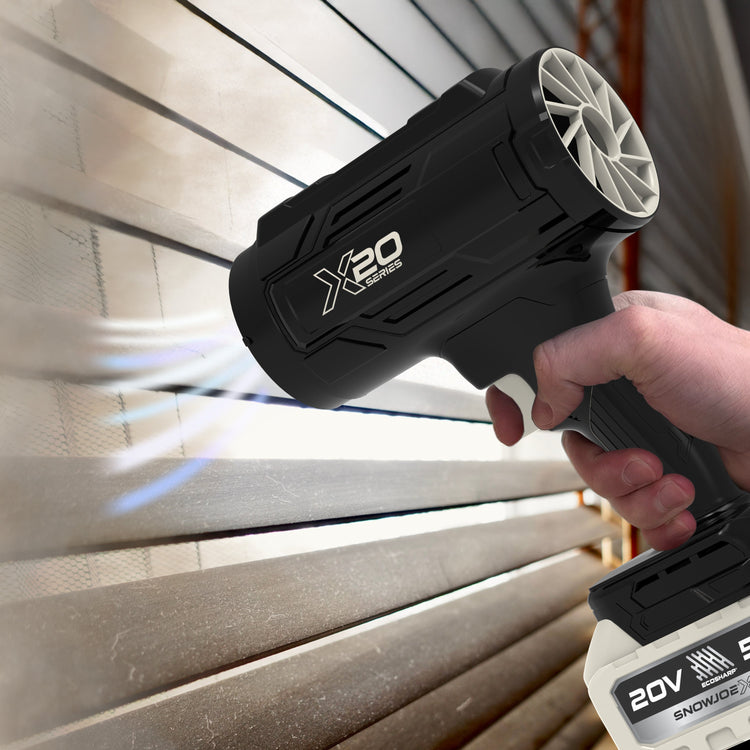 Black handheld power tool with 'X20' branding held by a hand against a wooden background.