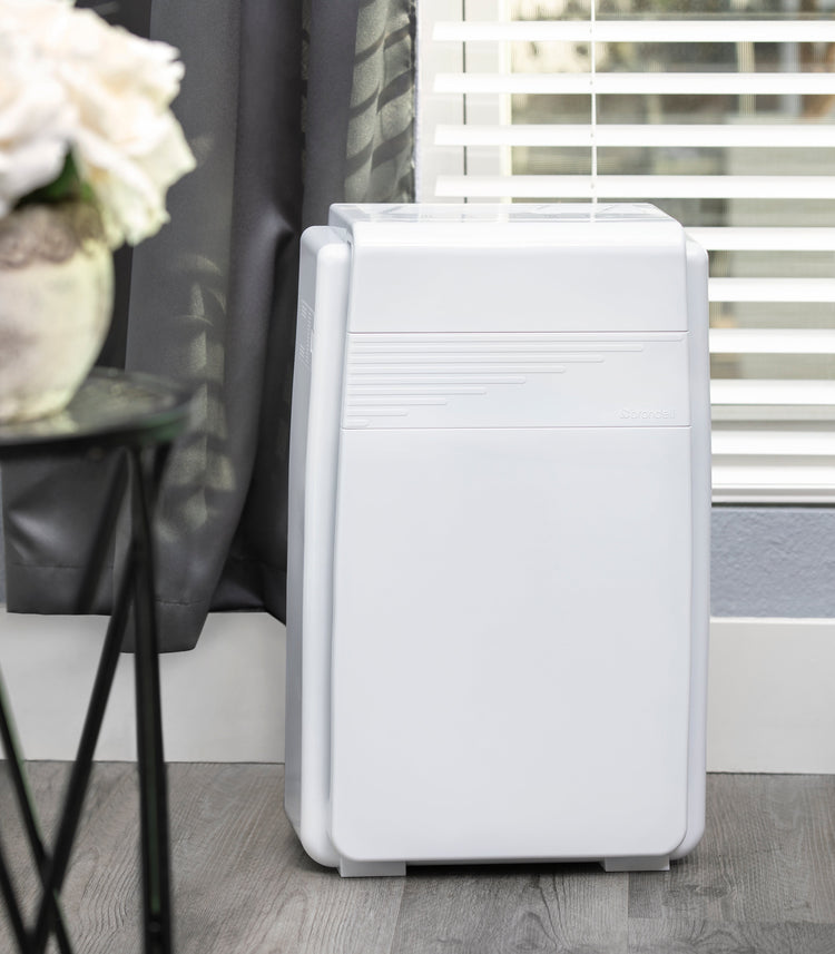 White air purifier on a wooden floor with a blurred background