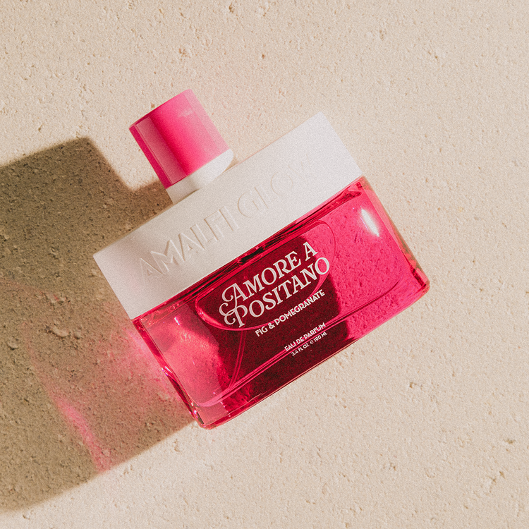 Red and white perfume bottle labeled 'Amore A Positano' on a beige background