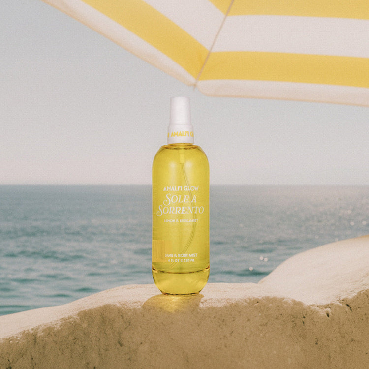 Yellow bottle with a white cap on a sandy surface near the ocean