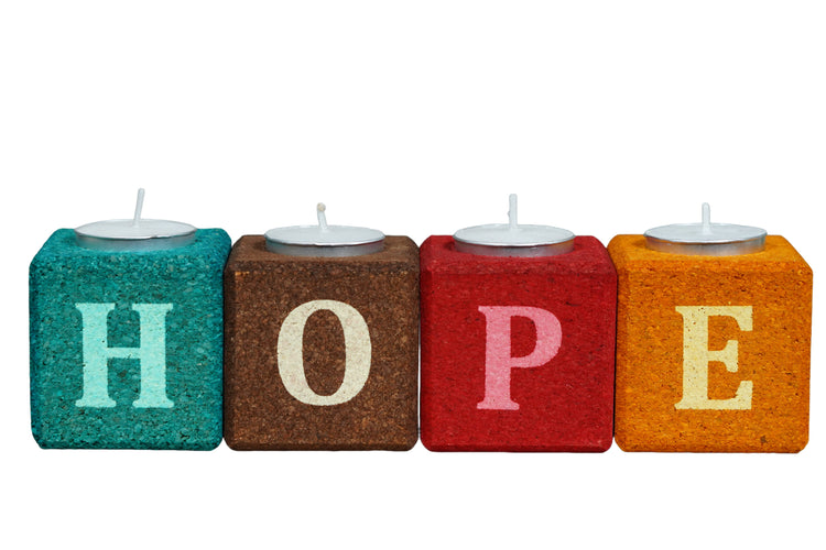 Colorful blocks spelling 'HOPE' with small candles on a white background