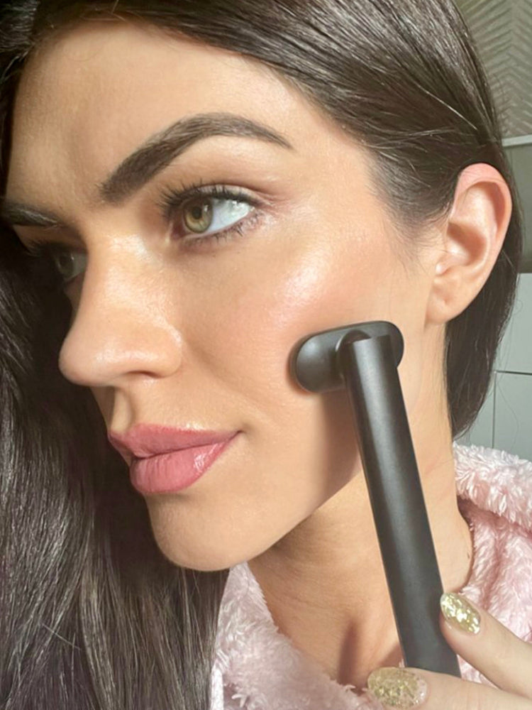 Woman applying makeup with a brush in a bathroom setting