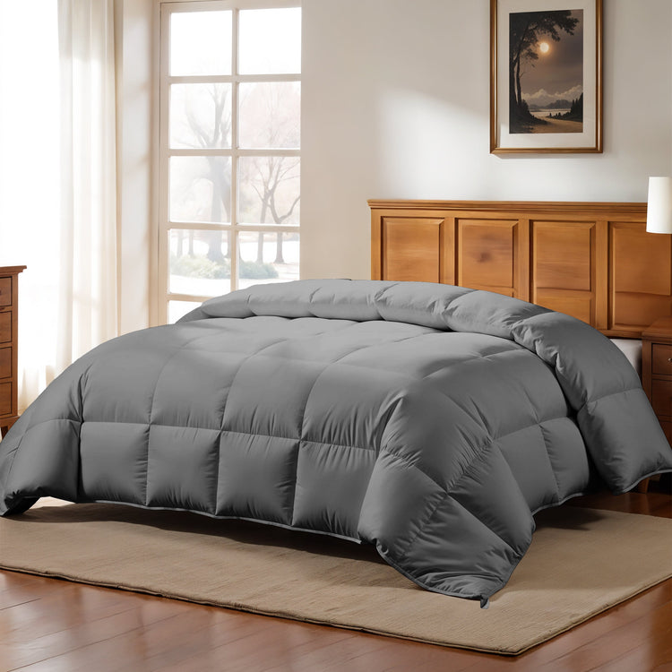 Gray comforter on a bed in a bedroom with wooden furniture and a window.