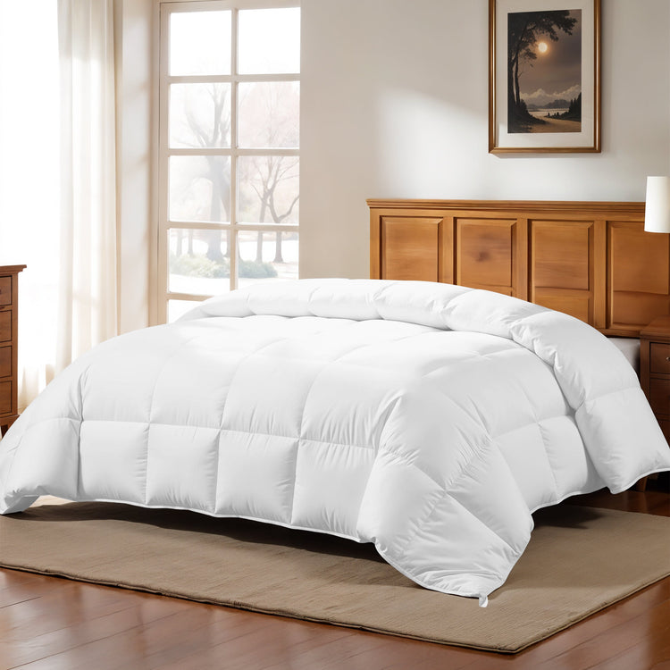 White comforter on a bed in a bedroom with wooden furniture and a window.