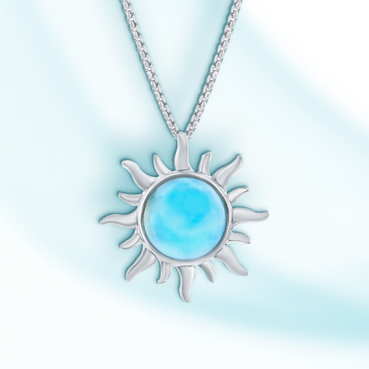 A sterling silver sun pendant necklace with a natural Larimar stone in the center, displayed against a light blue background.