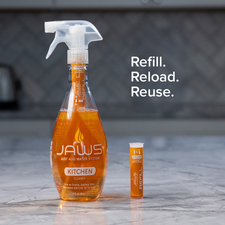 Orange cleaning spray bottle with a smaller refill container on a marble surface, with 'JAWS' branding.