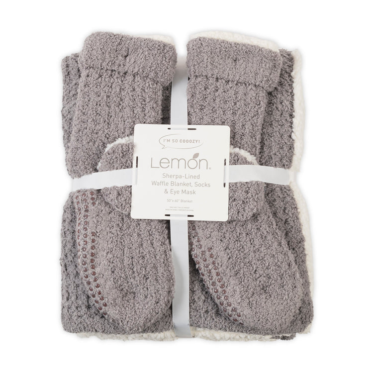 Gray textured blanket, socks, and eye mask set with Lemon label on a white background