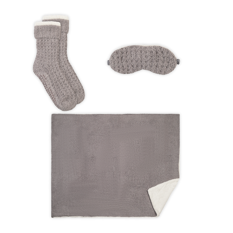 Gray textured sock, eye mask, and blanket set on a white background