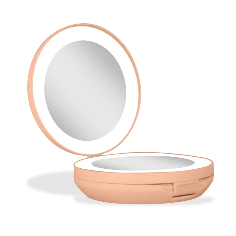 Compact mirror with a peach-colored frame on a white background