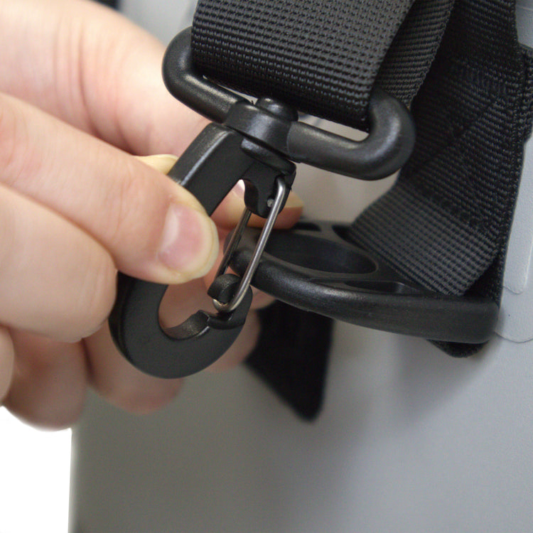 Hand adjusting a black belt with a carabiner clip on a neutral background