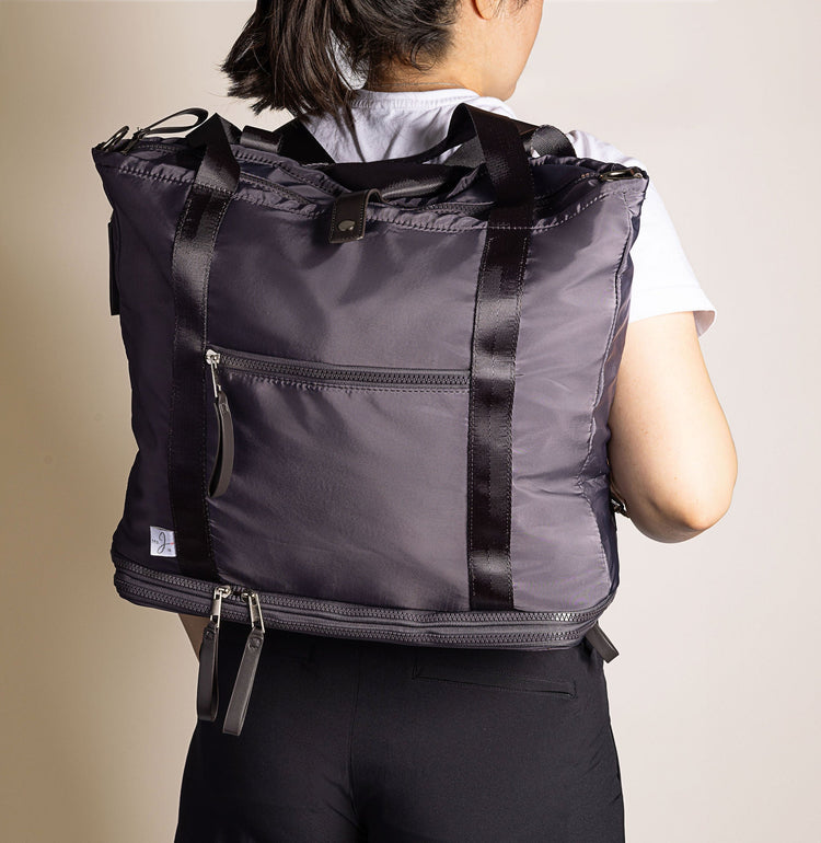 Person wearing a black and gray backpack with a neutral background