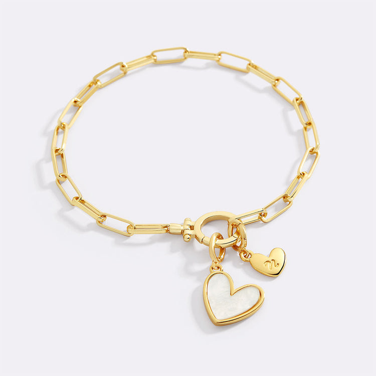Gold bracelet with heart-shaped charms on a light gray background