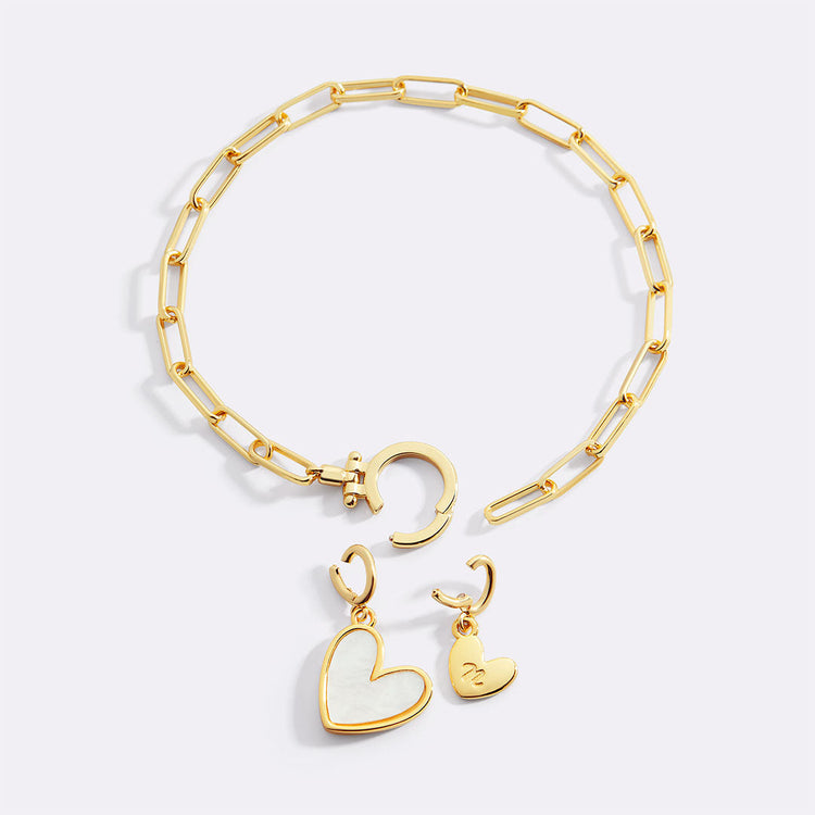 Gold bracelet with heart-shaped charms on a light gray background