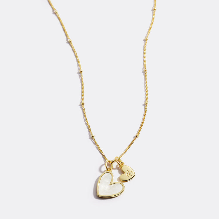 Gold necklace with a heart-shaped pendant on a light gray background
