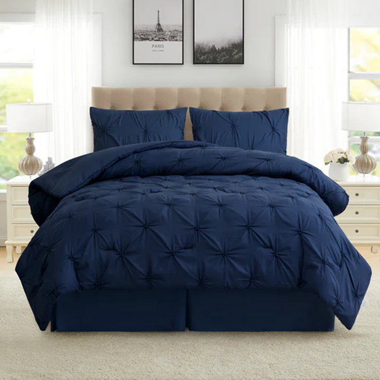 Navy blue comforter set on a bed in a bedroom with white walls and decor.