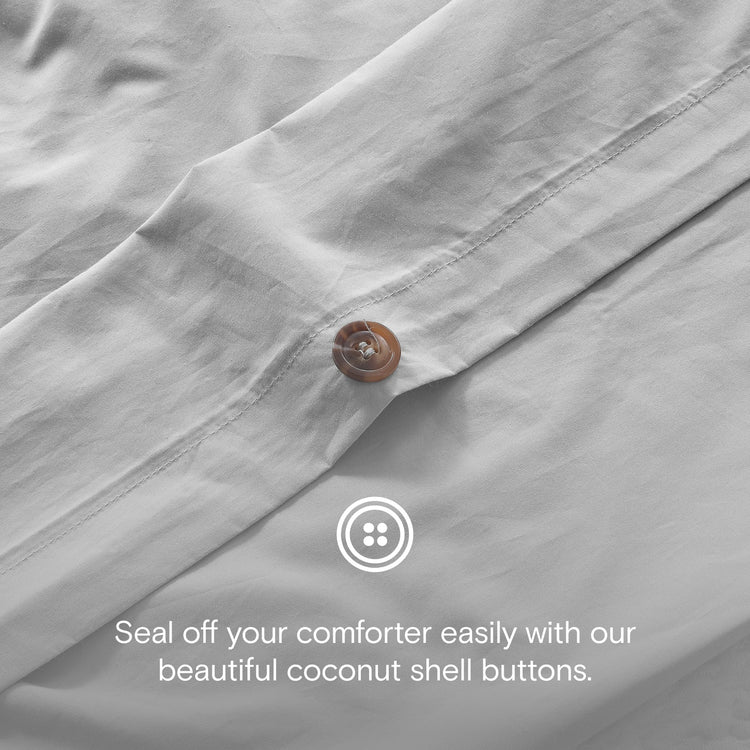 Close-up of a gray comforter with a coconut shell button and text overlay.