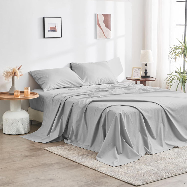 Gray bedding set on a bed in a bedroom with side tables and decor.