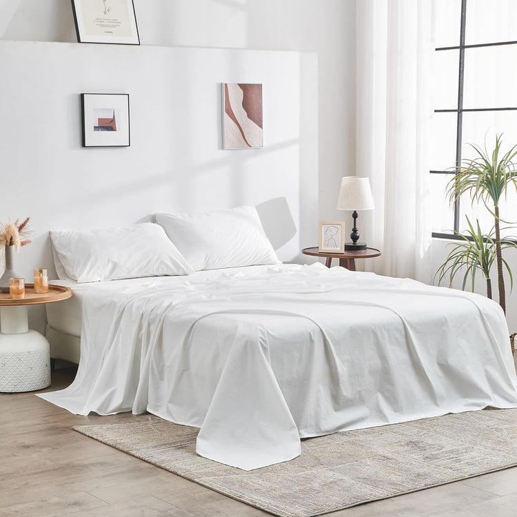 White bedding set on a bed in a bright bedroom with decor elements.