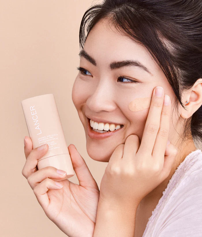Woman holding a skincare product with a beige background